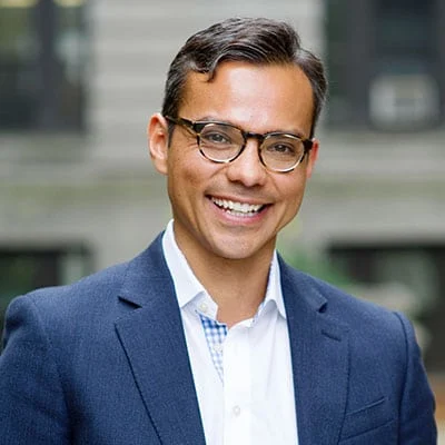 Dr. Ernest Gonzales standing outside in a suit smiling.