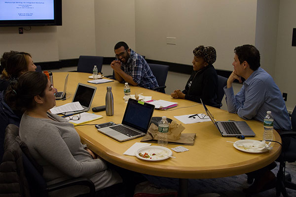 Associate Professor Rogério Pinto engages in discussion with students seated around a table.