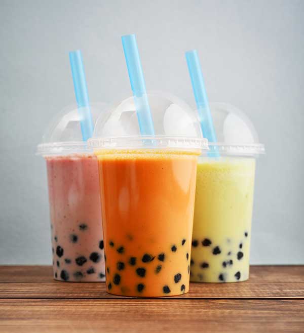 Three clear plastic cups with pink, orange, and yellow bubble tea.