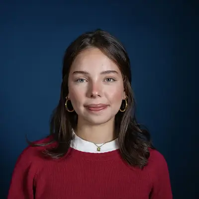Photo of Nicole Portmann Muño in front of a blue background.