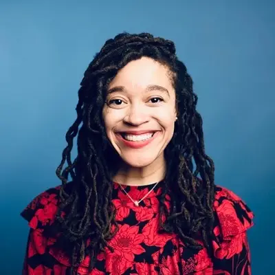 Photo of Ashley Cureton smiling on a blue background.