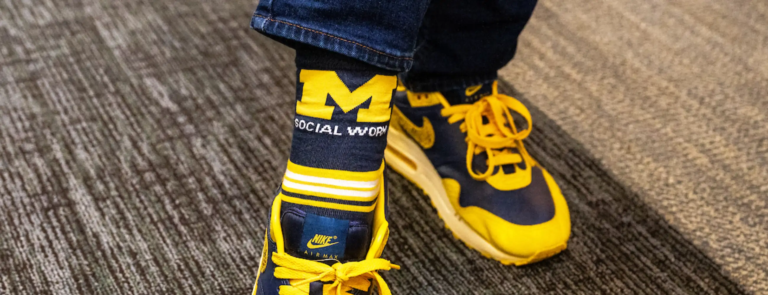 U-M School of Social Work alumni showing off their maize and blue shoes and socks.