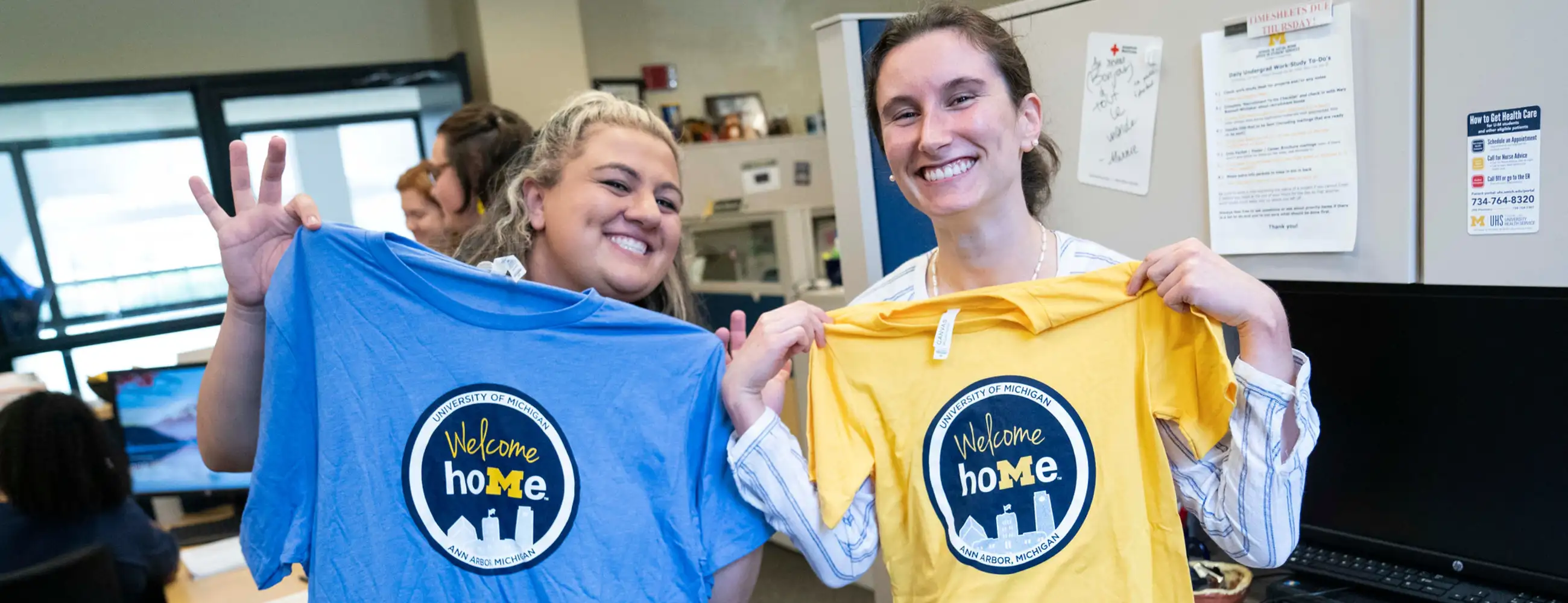 Two people holding "welcome home" shirts