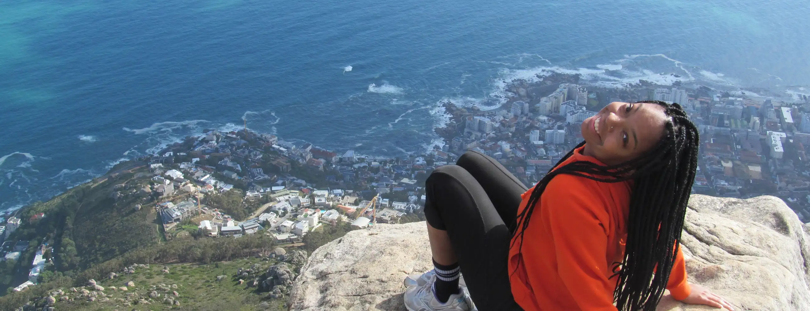 Person sitting on a rock at the top of a mountain