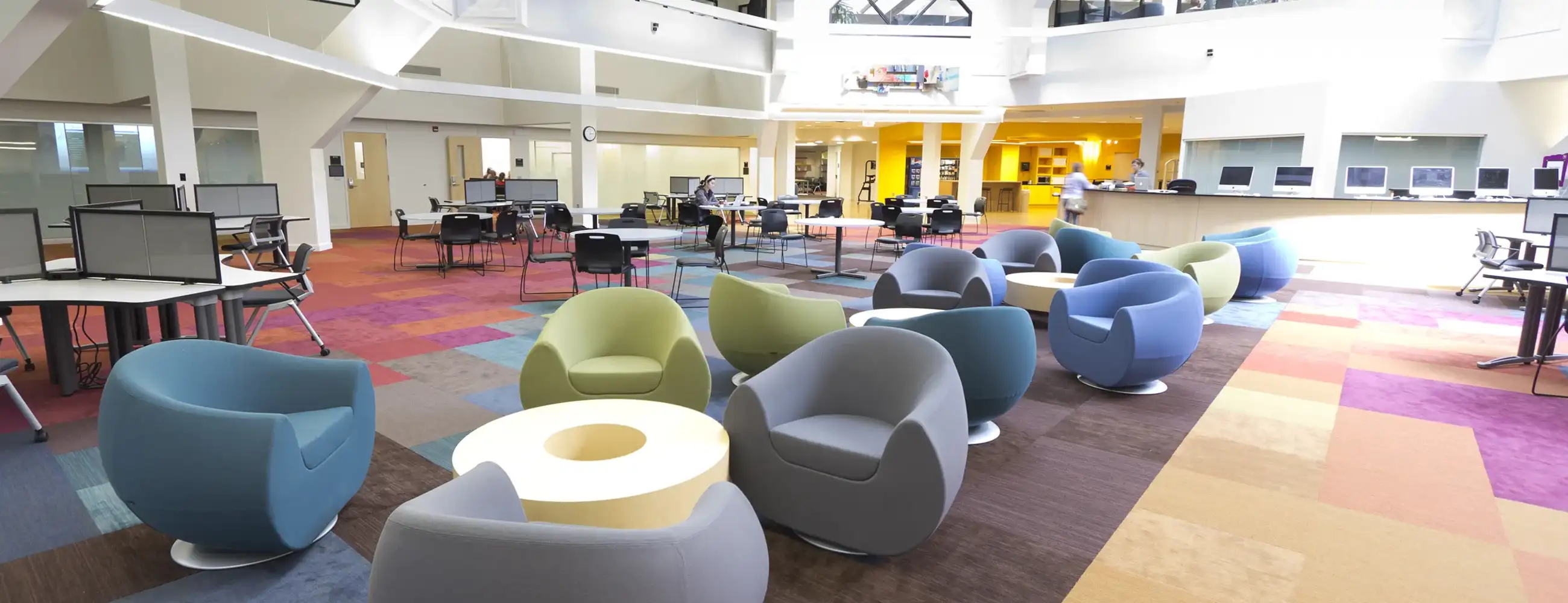 Photo of the SSW Atrium. The room is airy with brightly colored chairs and floor.
