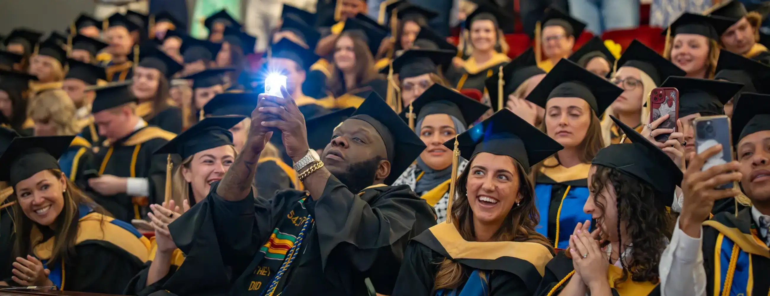 Graduating students at Hill Auditorium sitting and taking photos.