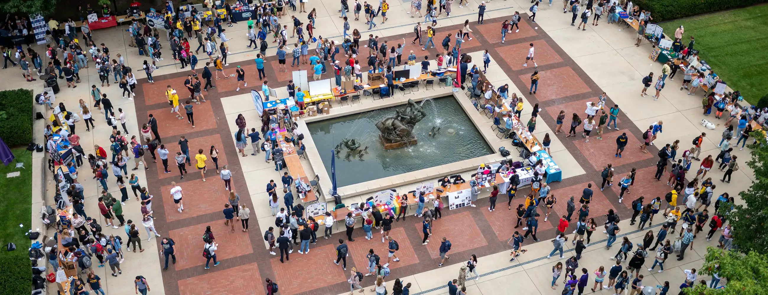 Aerial view of Festifall at Ingalls Fountain, with hundreds of students browsing rows of student organization tables around the fountain's bronze sculpture.