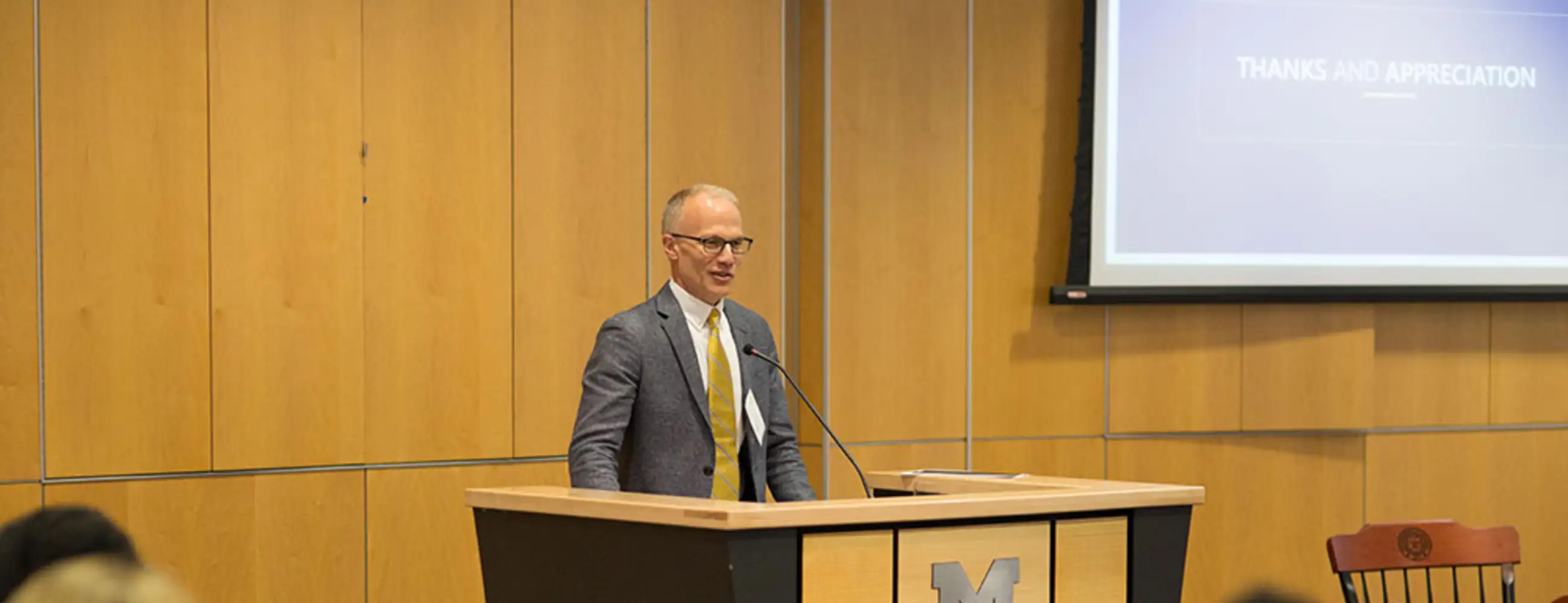 Todd Herrenkohl speaks at a podium with the University of Michigan School of Social Work logo during his installation as the Marion Elizabeth Blue Endowed Professor in Children and Families